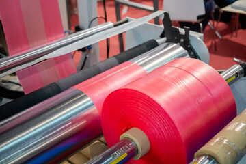 Moving roller with flat polyethylene pink film - automatic plastic bag making machine at...