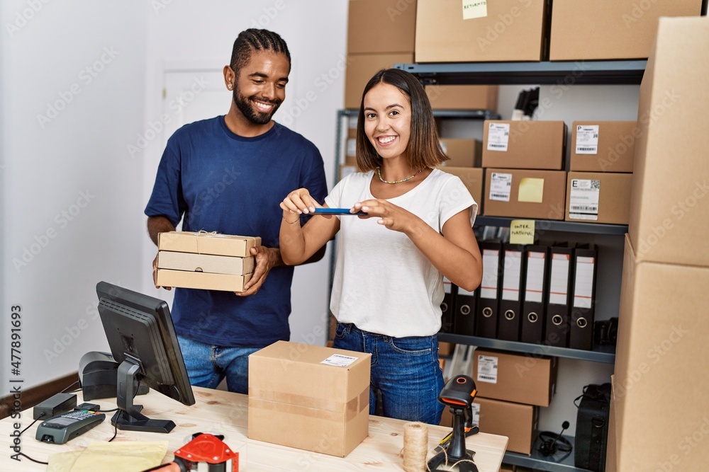 Wall mural Man and woman business partners scanning package using smartphone at storehouse