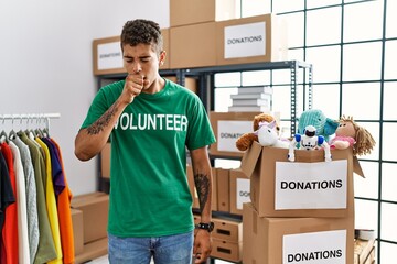 Young handsome hispanic man wearing volunteer t shirt at donations stand feeling unwell and coughing as symptom for cold or bronchitis. health care concept.