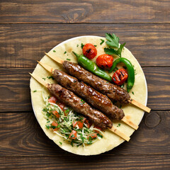 Turkish Adana Kebab with fresh vegetables on flatbread