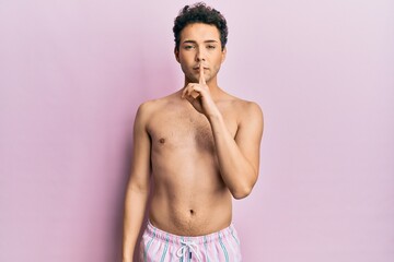 Fototapeta premium Young handsome man wearing swimwear shirtless asking to be quiet with finger on lips. silence and secret concept.