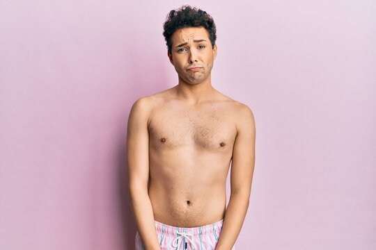 Young handsome man wearing swimwear shirtless depressed and worry for distress, crying angry and afraid. sad expression.