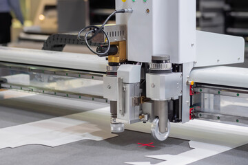 Digital flatbed cutter, plotter cutting white cardboard sheet at printer exhibition, trade show -...