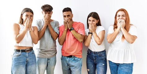 Group of young friends standing together over isolated background laughing and embarrassed giggle...