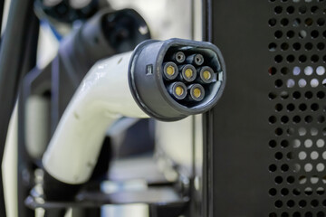 Electric charger of vehicle charging station with plug of power cable - close up view. Renewable, transport, technology, sustainable energy and futuristic concept