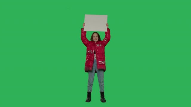 Teen girl holding placard cardboard isolated over chroma key. Female with white blank on green screen background . 4k video footage