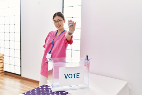 Young asian woman holding I voted badge at american election room - Powered by Adobe