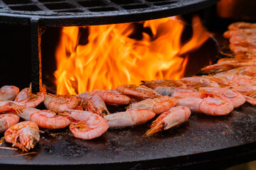 Process of grilling fresh red king prawns on brazier with hot flame at summer local food market -...