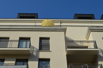 Façade d'immeuble avec un parasole sur terrasse.