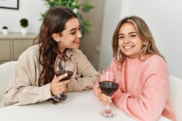 Young couple smiling happy toasting with red wine glass at home.