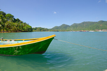 Floating green boat in the sea with mountains and blue sky background