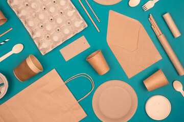 Flat lay with eco-friendly tableware and sustainable packaging. Kraft paper food packaging on green...