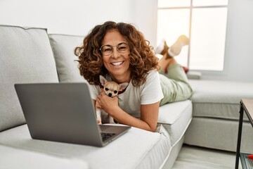 Middle age hispanic woman smiling confident using laptop at home