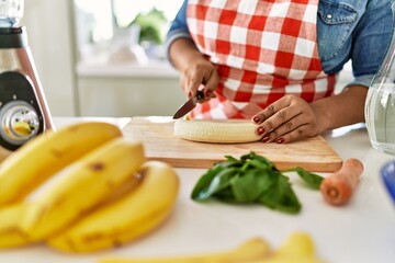 Hispanic brunette woman preparing fruit smoothie at the kitchen