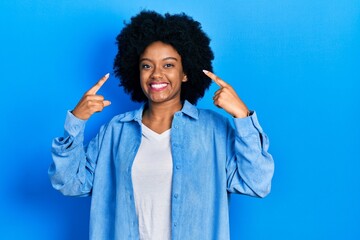 Fototapeta na wymiar Young african american woman wearing casual clothes smiling pointing to head with both hands finger, great idea or thought, good memory