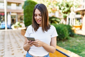 Young beautiful woman smiling happy outdoors on a sunny day using smartphone