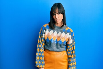 Young hispanic woman wearing casual winter sweater skeptic and nervous, frowning upset because of...