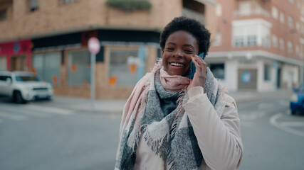 Fototapeta premium Young african american woman smiling confident talking on the smartphone at street