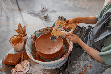 Skillful craftswoman making bowl in pottery workshop