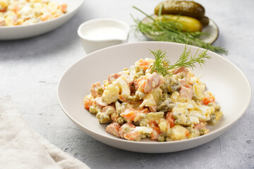 traditional east european dish for New Year's Eve - salad "Olivier" with potatoes, carrots, onion, peas, sausage, cucumbers, eggs and mayonnaise in a grey bowl