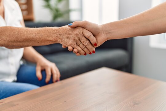 Senior grey-haired woman patient and psychology shake hands at psychology center