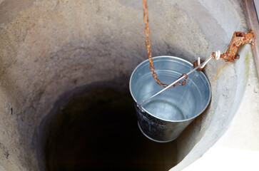 Metal bucket in draw-well in European village. Retro stone water well in rural area © supersomik