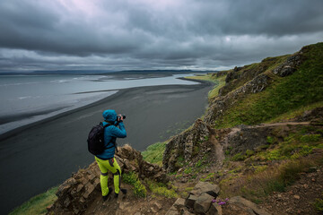 A tourist photographs a black beach on the Vatnsnes peninsula. Hvitserkur. Iceland