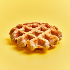  Single delicious waffle over yellow background