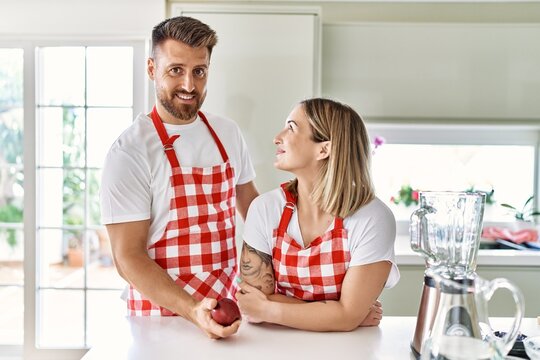 Young couple smiling confident holding red apple at kitchen
