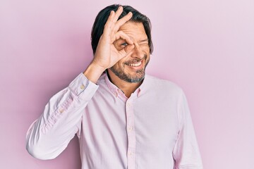 Obraz premium Middle age handsome man wearing business shirt smiling happy doing ok sign with hand on eye looking through fingers