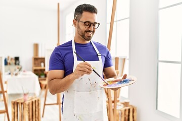 Young hispanic man smiling confident drawing at art studio