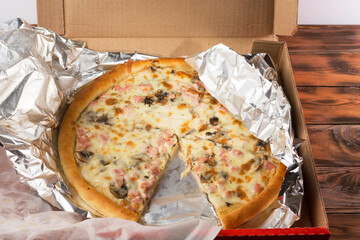 freshly baked pizza in a cardboard box and in foil