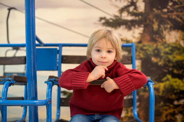 Cute toddler child, blond boy, sitting in old vintage ski lift