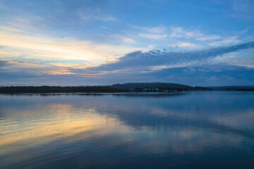 Soft and peaceful sunrise aerial waterscape with clouds and reflections
