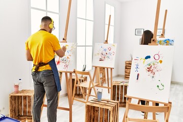 Young hispanic couple smiling happy listening to music and drawing at art studio.