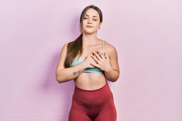 Young hispanic girl wearing sportswear smiling with hands on chest with closed eyes and grateful gesture on face. health concept.