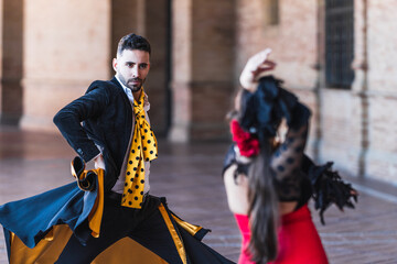 Selective focus on a man with a cape dancing flamenco with a woman outdoors