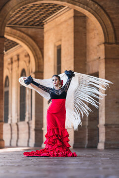 Woman in flamenco dress dancing while waving a cloth outdoors
