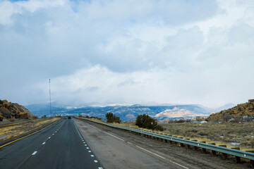 Dangerous covered roads and hazardous winter weather along a high rocky mountains I-40 road with winter snow covered landscape in the New Mexico