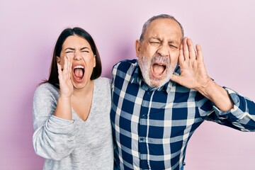 Hispanic father and daughter wearing casual clothes shouting and screaming loud to side with hand on mouth. communication concept.