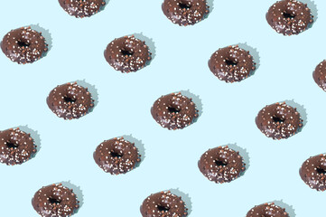 Chocolate donuts arranged in a pattern on a blue background. Dessert sweet food concept.
