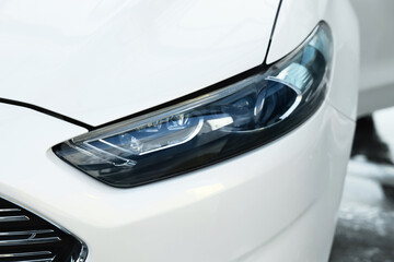 Luxury white car outdoors, closeup of headlight