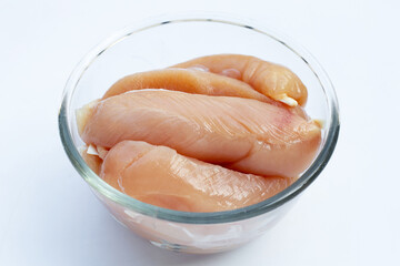 Raw chicken tenders in glass bowl on white background.