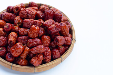 Dried Chinese jujubes in bamboo basket on white background.