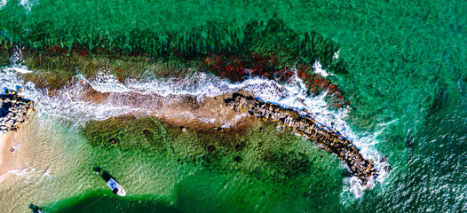 panoramic drone shot of coral reef in ocean and waves crashing on beach