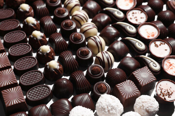 Many different delicious chocolate candies as background, closeup view