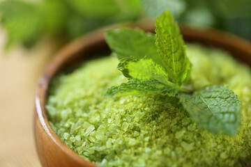 green salt in a round wooden bowl and sprigs of peppermint on a wooden table.salt with Peppermint...