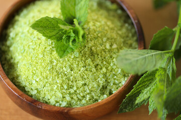 Peppermint salt.green sea salt in a round wooden bowl and sprigs of peppermint on a wooden table.salt with Peppermint extract. Natural cosmetics and aromatherapy for body