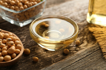 Soybeans and bowl of oil on wooden table, closeup
