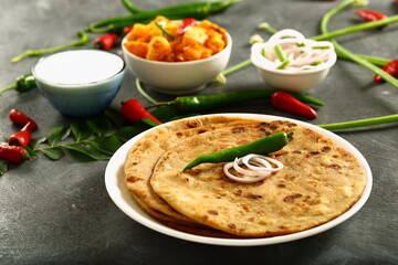 Indian vegetarian meal- healthy vegan diet - aloo paratha served with spicy potato curry and raita,.